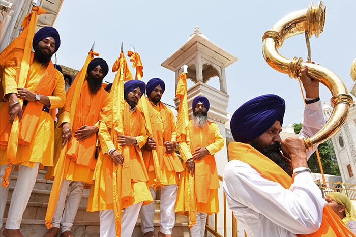 A devotee plays a musical instrument during a religious procession on the eve of 400th birth anniversary of Guru Teg Bahadur in Amritsar.