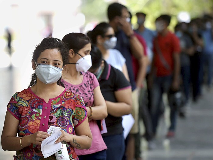 People above 18 stand in a queue to receive the first dose of COVID-19 vaccine at a vaccination centre in a government school, in New Delhi.