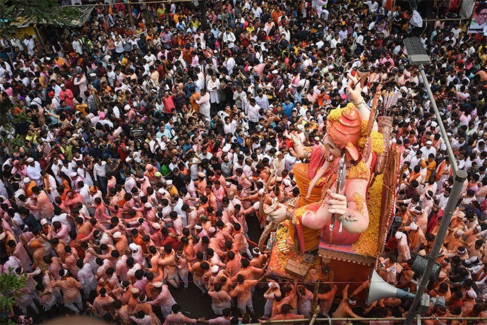 People watch as devotees carry an idol of Lord Ganesha for immersion, which in Mumbai