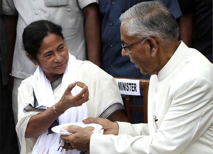 Mamata Banerjee accepts the sweets offered by Governor MK Narayanan after taking oath of office as Chief Minister of West Bengal. But the aftertaste of her oath would be much sweeter and long lasting as she has worked hard for over three decades for this day.