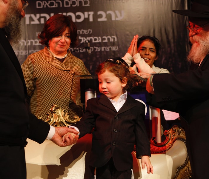 Much cheering and congratulating as another lock of hair is cut. Moshe, all of three, stands tall amid the adulation.  A year ago, Moshe was at the besieged Jewish centre where his parents lay dead. When he cried out for his nanny Sandra Samuel, she ignored gunfire and grenade explosions, charged up the stairs and whisked the boy away from the motionless body of his mother, to safety.  At Moshe?s Halakah Samuel says: "Everything is normal. It took a little bit of time, but now it's completely normal." (AP Photo)