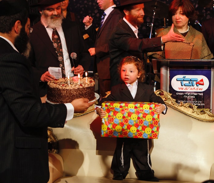 Happy Birthday. Moshe Holtzberg receives a gift for his third birthday. Hundreds of people joined the smiling child and his grandparents at the village outside Tel Aviv, to mark a year since the attacks. (AP Photo)