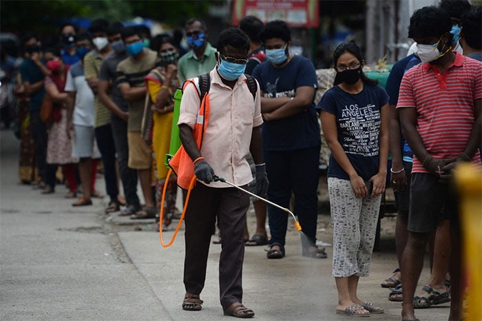 A health worker sanitizes the area while people wait to get coronavirus vaccine at a vaccination camp in Chennai