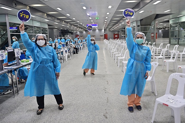 Health workers call for people to receive doses of the coronavirus vaccine at Bang Sue Central Station in Bangkok