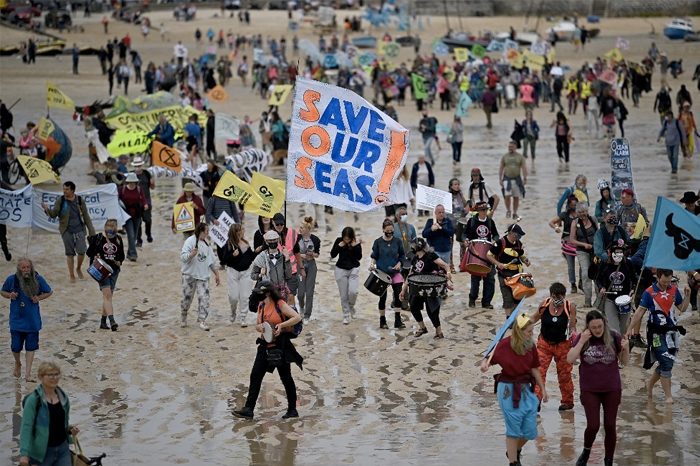 Activists take part in an Extinction Rebellion climate change protest march on the beach in St Ives, Cornwall on June 11, 2021.