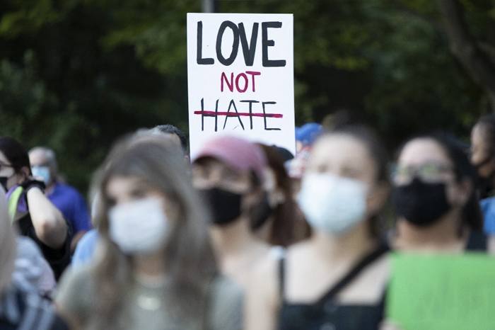 People hold a sign reading "Love Not Hate" at the London Muslim Mosque during the multi-faith march to end hatred, after a man driving a pickup truck struck and killed four members of a Muslim family in London, Ontario, Canada on June 11, 2021.