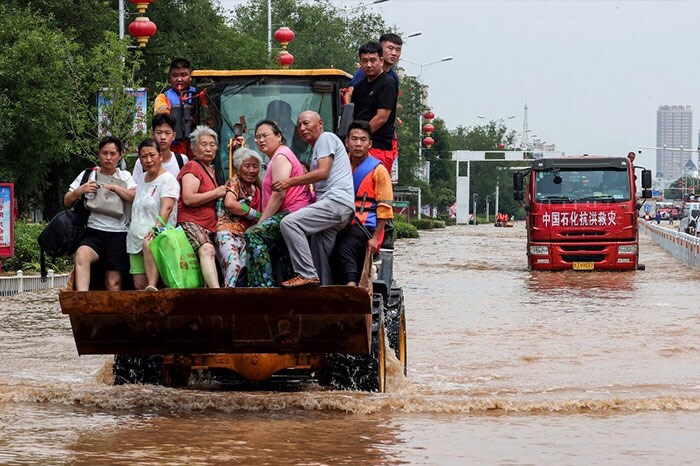 Rescuers evacuating residents with a loader at a flooded area in Weihui, Xinxiang city, in China's central Henan province.