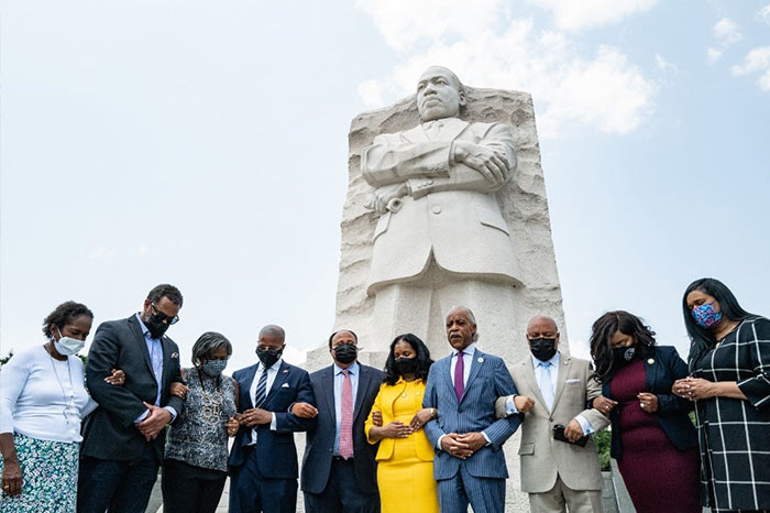 Martin Luther King III and others stand with locked arms praying at the Martin Luther King, Jr. Memorial on July 28, 2021 in Washington, DC.