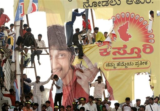 People sit on an advertisement hoarding as they watch an idol of Hindu goddess Chamundeeswari, unseen, being carried on an elephant through the city streets as part of the last day Dussera celebrations in Mysore.