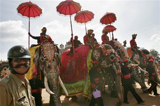 A police official stands guard as mahouts lead decorated elephants through the city streets as part of the last day Dussera celebrations in Mysore.