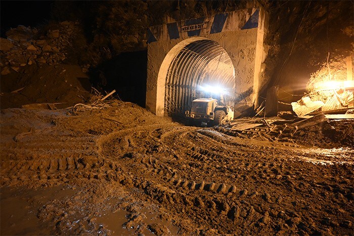 A bulldozer and rescue teams work at night at the entrance of a tunnel blocked with mud and debris during rescue operations in Tapovan of Chamoli district.