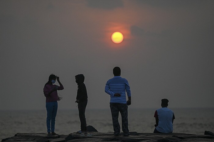 People are silhoutted near the sea front during sunrise in Pondicherry.