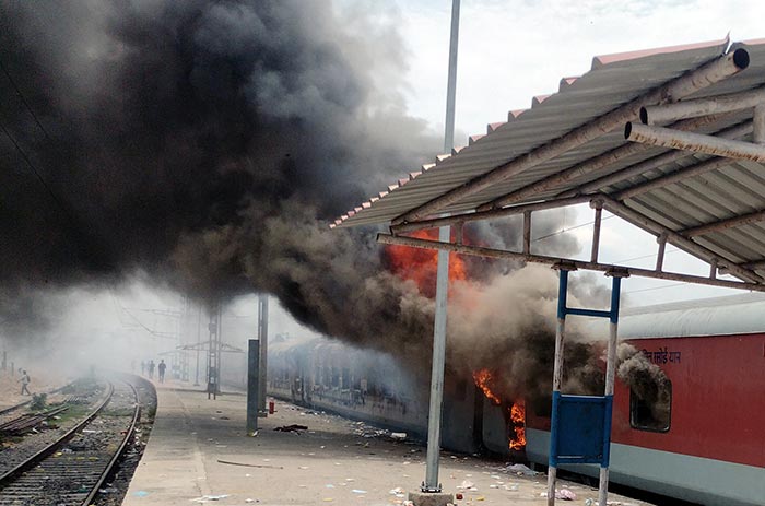 Smoke and flames billow out of a train after it was set on fire during a protest against the Agnipath scheme for the armed forces, in Bihar's Lakhisarai.