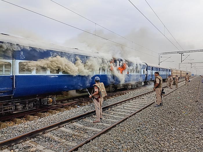 Smoke billows from a train in UP's Ballia after it was set on fire by those protesting against the 'Agnipath' scheme.