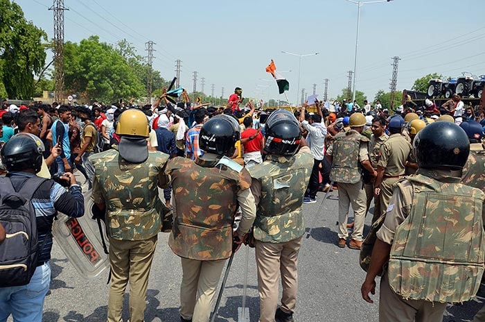 Police personnel stand guard during a demonstration in Mathura against the Agnipath scheme.