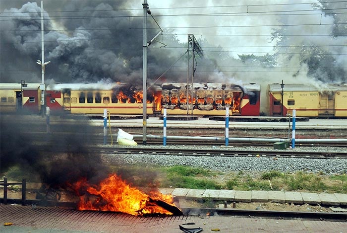 Flames erupt from a train that is set on fire during protests against the Agnipath scheme, at Danapur Railway Station in Patna.