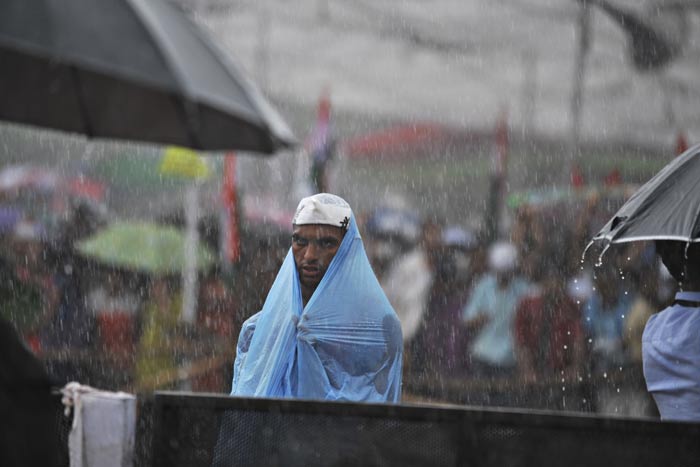 A supporter of Anna Hazare stands in the rain at Ramlila Ground.