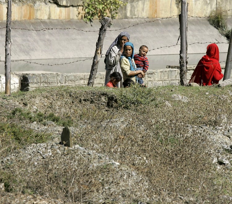 In this photo taken on October 7, 2009, local Kashmiri villagers walk past a graveyard containing unidentified dead at Bimyar, about 96 kilometers west of Srinagar. Human rights workers say that in the past 18 months they have identified dozens of burial grounds where they believe Indian security forces dumped more than 2,400 corpses. (AP Photo)