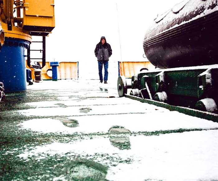 A crew member of the Akademik Shokalskiy walks on the snow-covered aft deck of the stranded ship in the Antarctic on December 29, 2013.