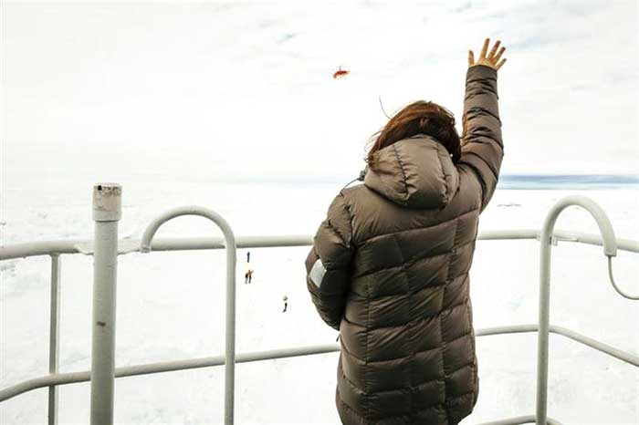 Nicole De Losa, a passenger on board the stranded ship waves to a helicopter sent from the Chinese icebreaker Xue Long (Snow Dragon) to assess ice conditions around the Russian Ship, in East Antarctica on December 29, 2013.