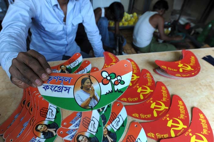 A man presents a sun caps carrying Trinamool Congress party symbol while other party symbols are seen on sale at a shop in Kolkata, on March 9, 2011.<br/><br/> The state assembly election of West Bengal will take place in six phases starting from April 18 2011, the counting of votes will take place on May 13, 2011. (AFP)