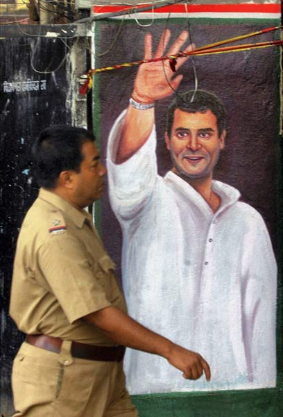 A policeman walks past a wall painting of AICC General Secretary Rahul Gandhi in Kolkata created for the upcoming assembly elections in West Bengal. (PTI)
