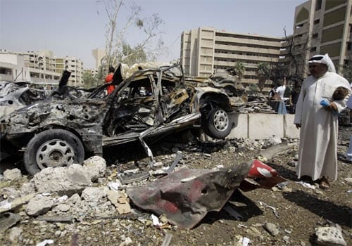 Debris: An Iraqi man stands amid debris and burnt cars at the scene of a massive explosion in front of the foreign ministry (background) on Wednesday. (AFP)