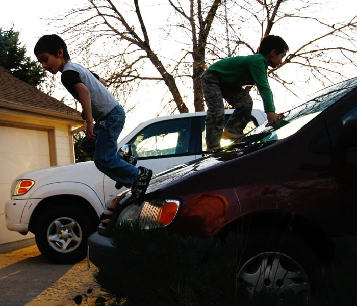 Falcon Heene (L) climbs over the family car with brother Ryo,&nbsp;outside their home. (AFP image)