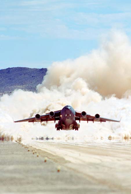 Boeing C-17 takes off from a rough strip.