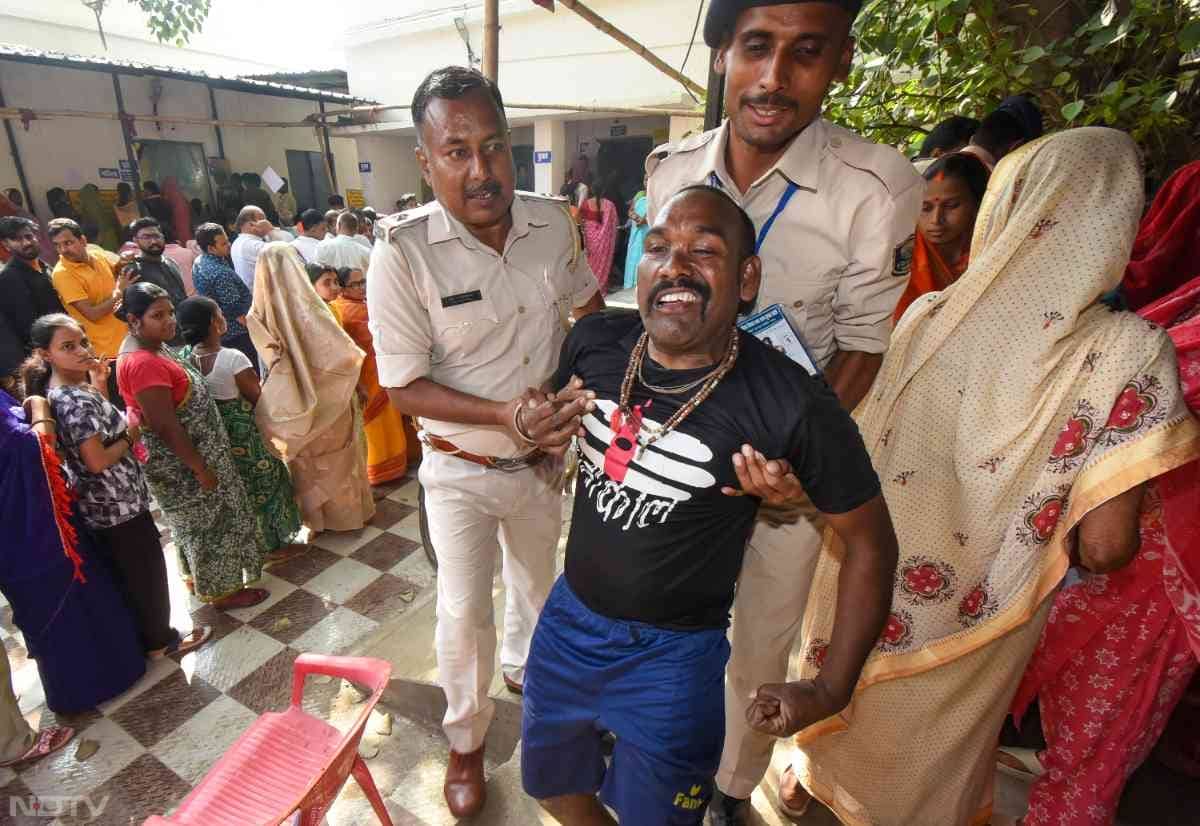 मतदान केंद्र पर मौजूद सुरक्षाकर्मियों को व्‍हीलचेयर पर पहुंचे शख्‍स को मतदान केंद्र के अंदर आने में मदद की.