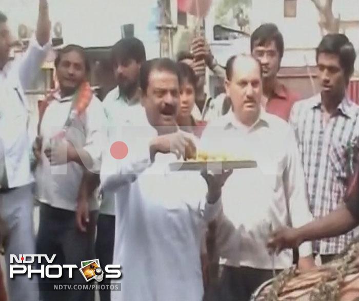 A supporter of Samajwadi Party distributes sweets in Meerut.