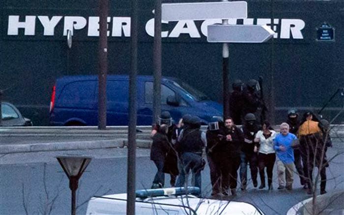 Security officers escort released hostages after they stormed a kosher market to end a hostage situation in Paris on Friday. (Associated Press)