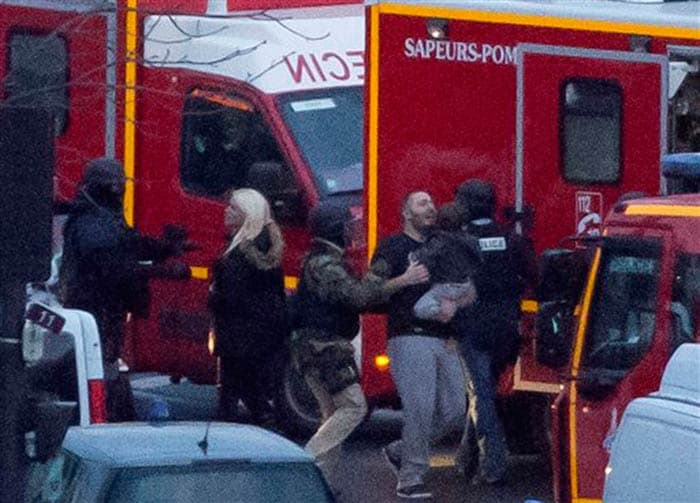 A security officer directs released hostages after they stormed a kosher market to end a hostage situation in Paris on Friday. (Associated Press)