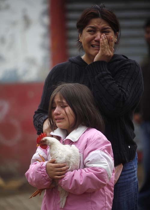 Heroism and banditry mingled on Chile's shattered streets on Sunday as rescuers braved aftershocks digging for survivors and the government sent soldiers and ordered a nighttime curfew to quell looting.<br><br>In this picture, residents cry after looters set fire to a supermarket next to their house in Constitucion. (AP Image)