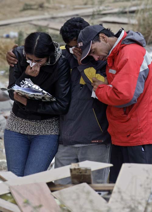 In Concepcion, the largest city in the disaster zone, a new, 15-story apartment building toppled onto its side.<br><br>Relatives of earthquake victims react outside a destroyed building in Concepcion. (AP Image)