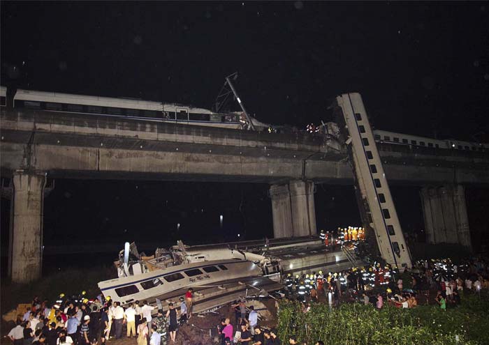 A preliminary investigation by the Zhejiang provincial government showed that four coaches of the moving train fell off the viaduct, Xinhua said. The cars plunged about 65 to 100 feet (20 to 30 meters) from the elevated section of track, it said.<br><br>Photos taken at the scene showed one badly damaged car lying on its side by the viaduct and another car leaning against the viaduct after landing on its end.<br><br>In this picture, emergency workers and civilians search for passengers from the wreckage of the train crash in Wenzhou in east China's Zhejiang province, Saturday, July 23, 2011. A Chinese bullet train lost power after being struck by lightning and was hit from behind by another train, knocking two of its carriages off a bridge, killing at least 35 people and injuring 191, state media reported. (AP Photo)