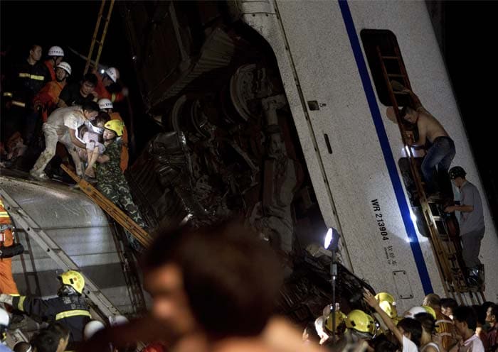 Early Sunday, Chinese President Hu Jintao and Premier Wen Jiabao called for an all-out effort to rescue passengers still trapped in the wreckage hours after the collision, Xinhua said. China Central Television later said the search-and-rescue operation had ended by 4 a.m. Sunday.<br><br>In this picture, emergency workers and others carry an injured passenger, at left, from the wreckage of one of two train carriages knocked off a bridge following the train crash in Wenzhou in east China's Zhejiang province, Saturday, July 23, 2011. A Chinese bullet train lost power after being struck by lightning and was hit from behind by another train, knocking two of its carriages off a bridge, killing at least 35 people and injuring 191, state media reported. (AP Photo)