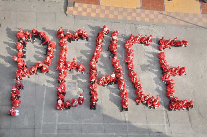 Children dressed up Santa Claus sit in a formation that reads peace during Christmas celebrations at a school in Moradabad. (PTI Photos)