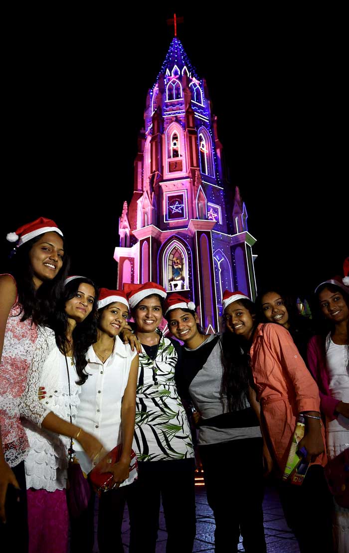 A group of girls pose infront of an illuminated St Basilica church - Christmas celebration in Bengaluru, celebrating the spirit of christmas. (PTI Photos)