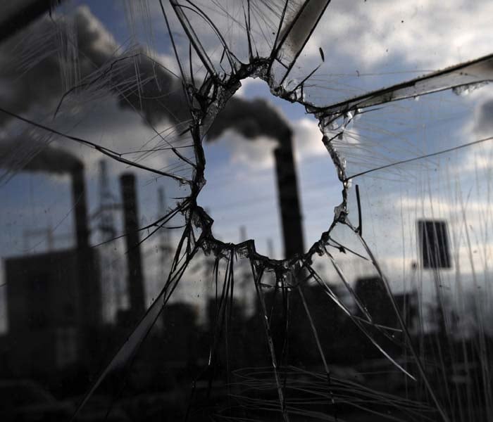 Smoking chimneys of a power plant are seen through a broken glass of a bus stop where several Greenpeace activists take their camp at one of the top platforms of powerplant chimney on December 2, 2008 in Patnow, some 80 kilometers east of city of Poznan.(AFP photo)