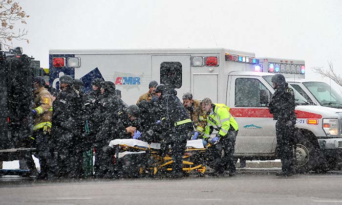 Emergency personnel transport an officer to an ambulance after reports of a shooting near the Planned Parenthood clinic Friday, Nov, 27, 2015, in Colorado Springs