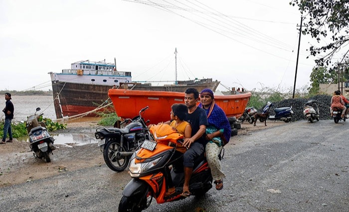 कच्छ: कच्छ जिले के मांडवी में शुक्रवार को चक्रवात बिपरजॉय के लैंडफॉल के बाद स्थिति सामान्य होने के बाद लोग मांडवी बंदरगाह से गुजरते हुए. (पीटीआई फोटो)