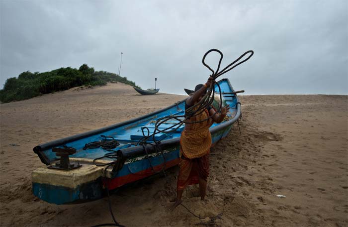 A woman secures a boat before evacuating from Donkuru village in Srikakulam district, Andhra Pradesh.