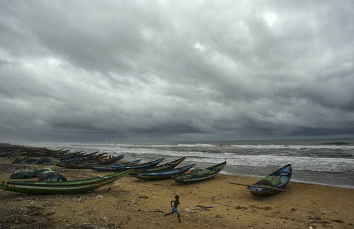 In this picture, young fishermen run past fishing boats anchored on the shore after cyclone Laila's alert in Puri, Orissa. (AP Photo)