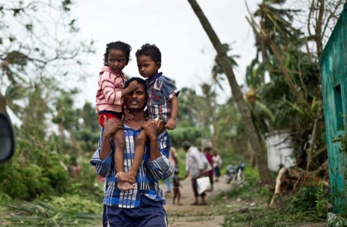 "Very severe" cyclonic storm Phailin made landfall near Gopalpur on Odisha coast on Saturday night with wind speed of around 200 kilometres per hour, causing very heavy rain in most parts of the state. Seen here,  a man carries his children at Sonupur village around 15 kms from Gopalpur in Odisha.