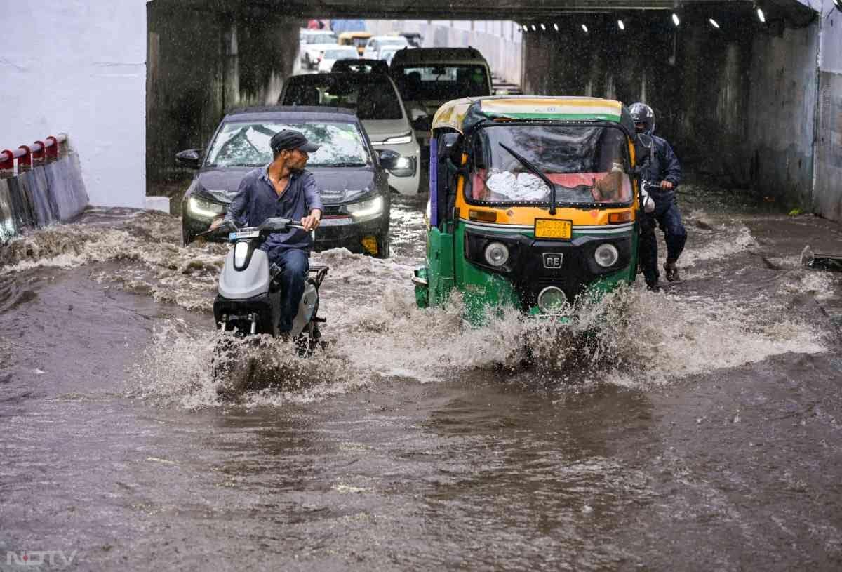 दिल्ली के गाजीपुर इलाके में भारी बारिश के बाद पानी भर गया, लोग पानी से भरी सड़क से गुजरने को मजबूर हैं
