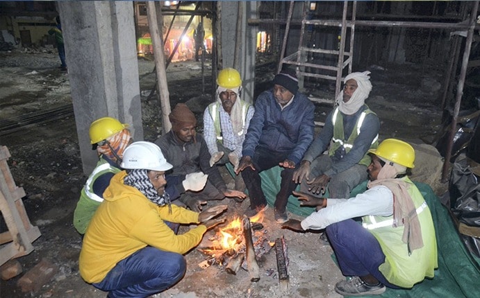 मिर्जापुर में एक निर्माण स्थल पर ठंड से बचने के लिए अलाव के पास बैठे कुछ मजदूर. (फोटो: पीटीआई)