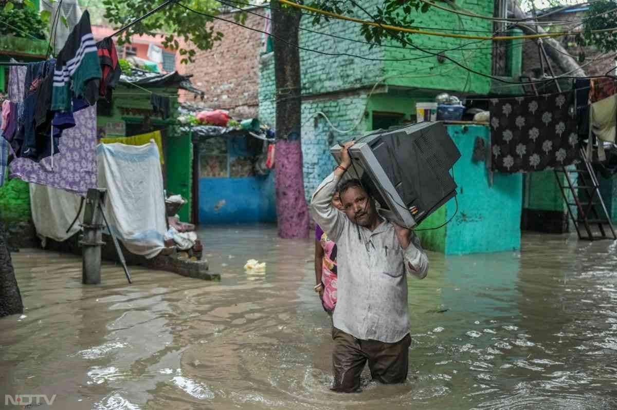 इलेक्‍ट्रॉनिक आइटम्‍स को पानी से बचाना बड़ी चुनौती है. ऐसे में एक शख्‍स टीवी लेकर सुरक्षित स्‍थान पर पहुंचाने की कोशिश करता नजर आया.