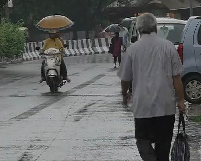 Motorists and pedestrians take shelter under umbrellas during the rainfall.