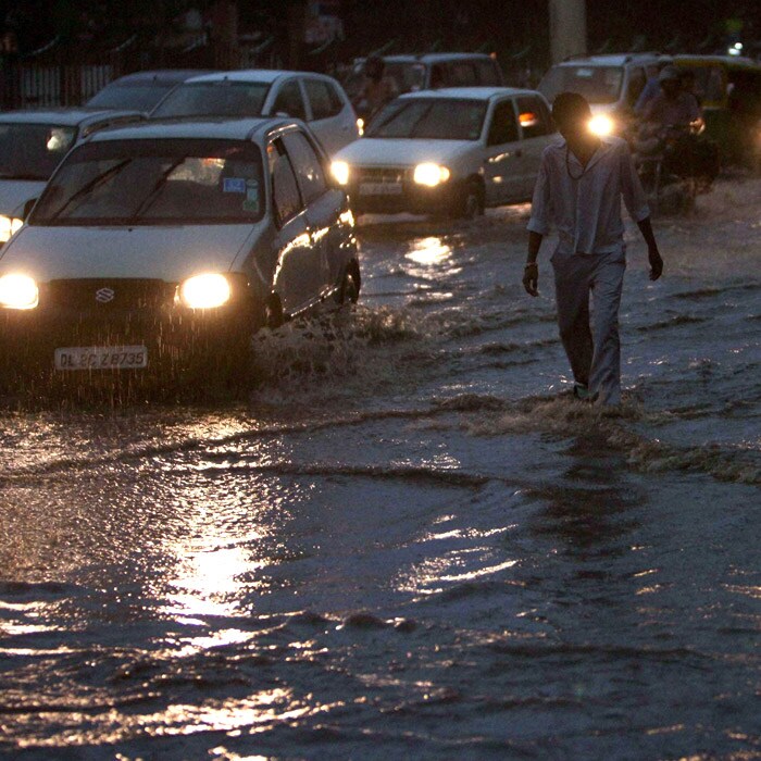 A man wades through a flooded and congested street after a downpour in New Delhi. The construction waste lying on roads went into drains in some areas, leading to waterlogging while dug-up roadsides with heaps of rubble caused problems for motorists. (PTI Photo)